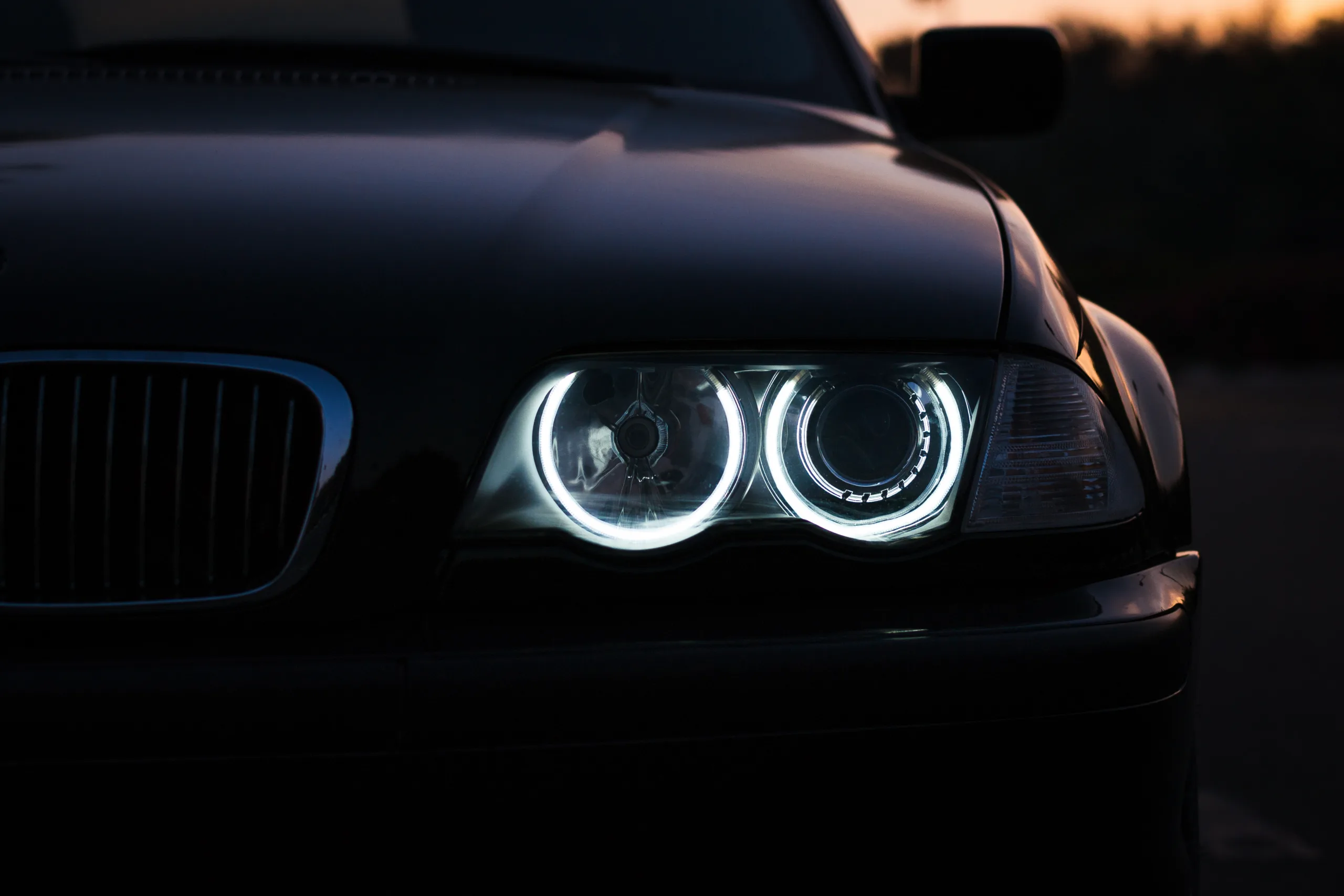 Silhouette of a black sports car with headlights on black background